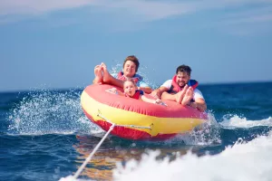excited friends, family having fun, riding on water tube during summer vacation
