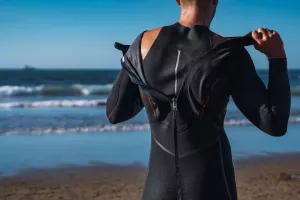 The man removes the wet neoprene from his wet body, the neoprene is very elastic and it is also resistant.