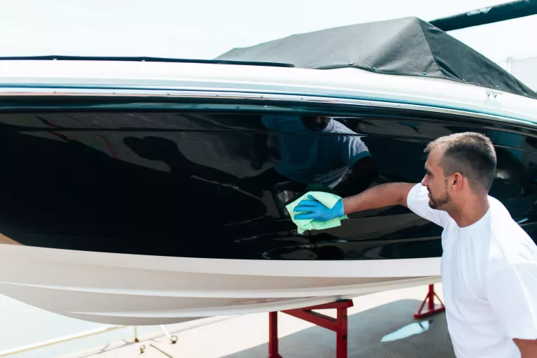 Boat maintenance - A man cleaning boat with cloth. Selective focus.