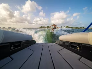 male wake surfing wave behind boat at sea